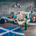 A person reaching for a bottle of beer in a messy flat alongside the Scottish Flag