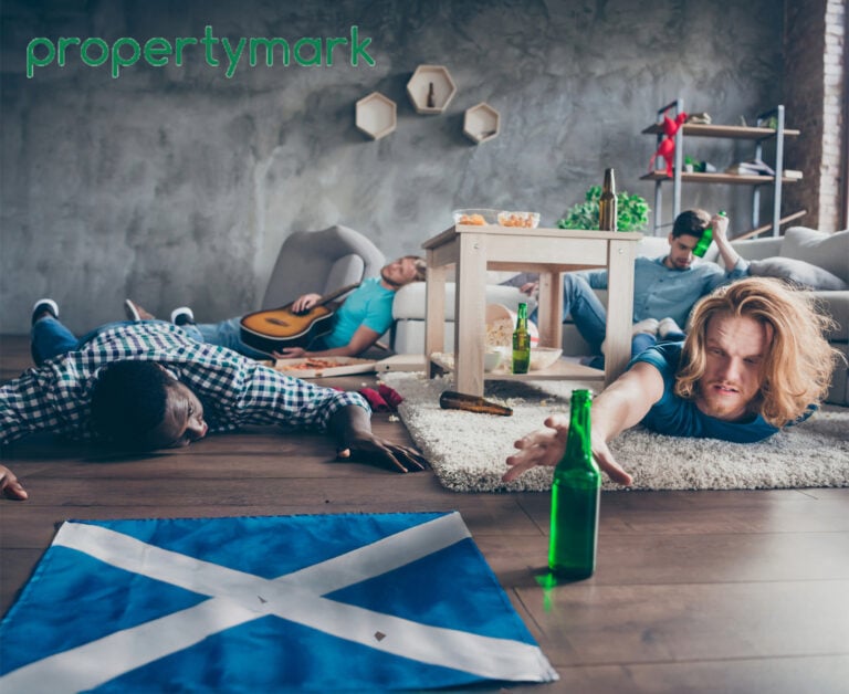 A person reaching for a bottle of beer in a messy flat alongside the Scottish Flag