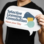 A man holding a sign saying Selective Licensing Constulation, have your say