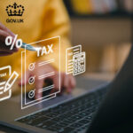 A person writing on a digital screen of a laptop showing Tax and a percentage sign, Gov.uk logo