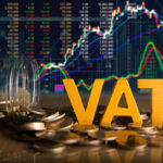 VAT sign, money coins and a digital graph in the background
