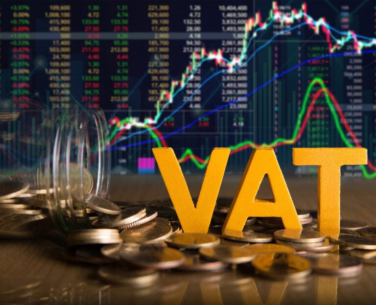VAT sign, money coins and a digital graph in the background
