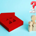 A red model house, wooden figures and a question mark