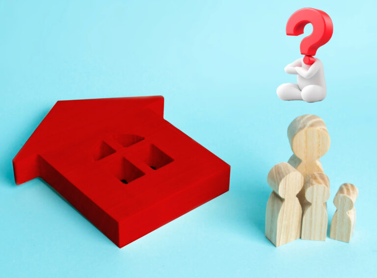 A red model house, wooden figures and a question mark