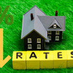 Arrow pointing down next to a house, rates and a percentage sign on a green grass background