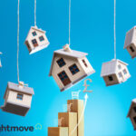 Model houses hanging on rope with a blue background, Rightmove logo and stepping blocks with supermarket trolleys balancing on top