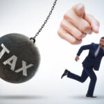 A person running, a finger pointing, and Tax written on a demolition wrecking ball