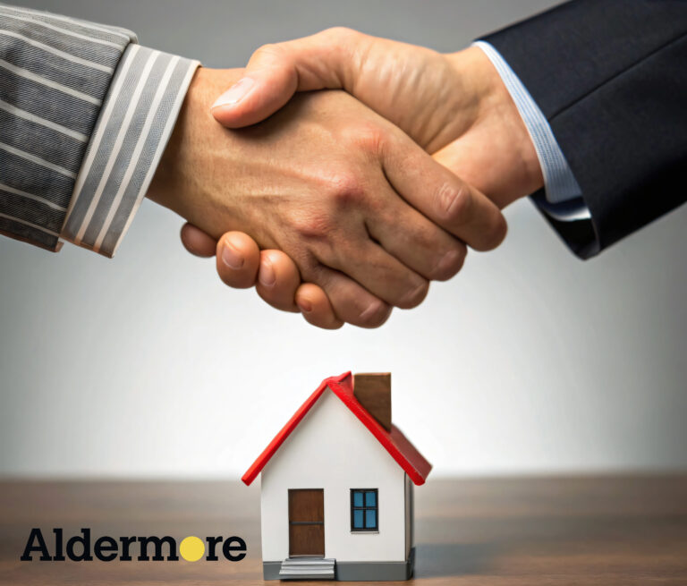 People shaking hands on top of a small house