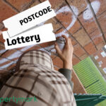 A person doing graffiti on a wall, in a housing estate and postcode lottery text