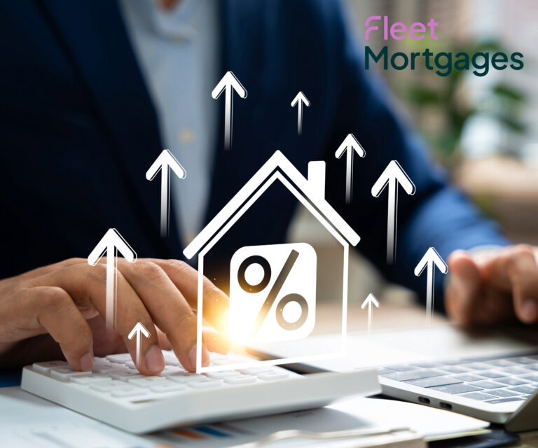 A businessman working on a laptop and a calculator, a digital image shape of a house with a percentage sign and arrows pointing upwards