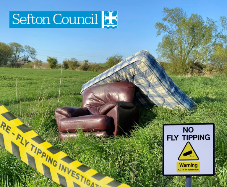 A mattress and leather armchair dumped in a field with a yellow warning no fly tipping sigh