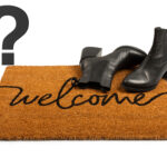 A welcome mat with boots and a question mark