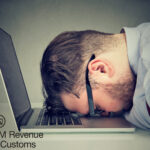 Frustrated man with head on laptop over HMRC digital tax requirements