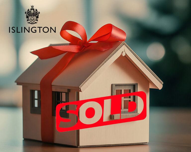 A wooden model house with a bow and a sold sign