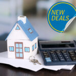 A house, calculator and keys on some papers on a desk