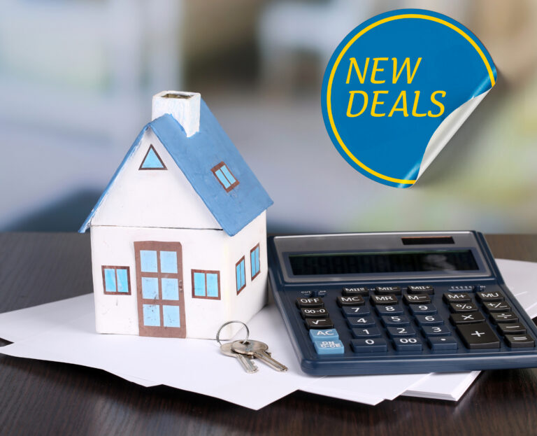 A house, calculator and keys on some papers on a desk