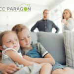 Two children sitting on a sofa with their parents standing behind them