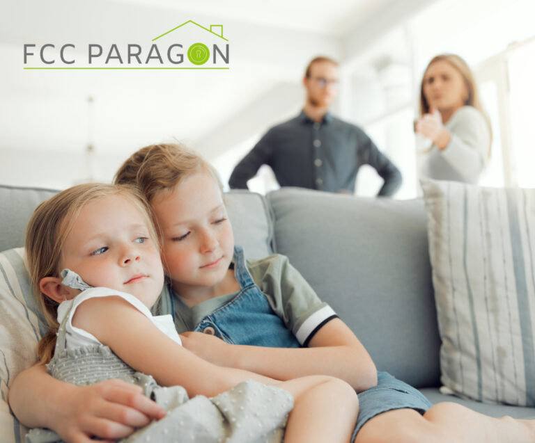 Two children sitting on a sofa with their parents standing behind them