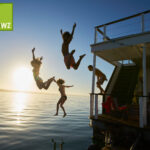 People jumping from a ship and a sunset in the background