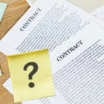 Contract papers with a question mark sticky note symbolizing tenancy agreement uncertainty.