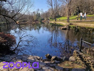A lake and woodland area with people walking by