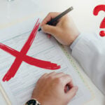 A person writing on a form with a Red cross and question mark