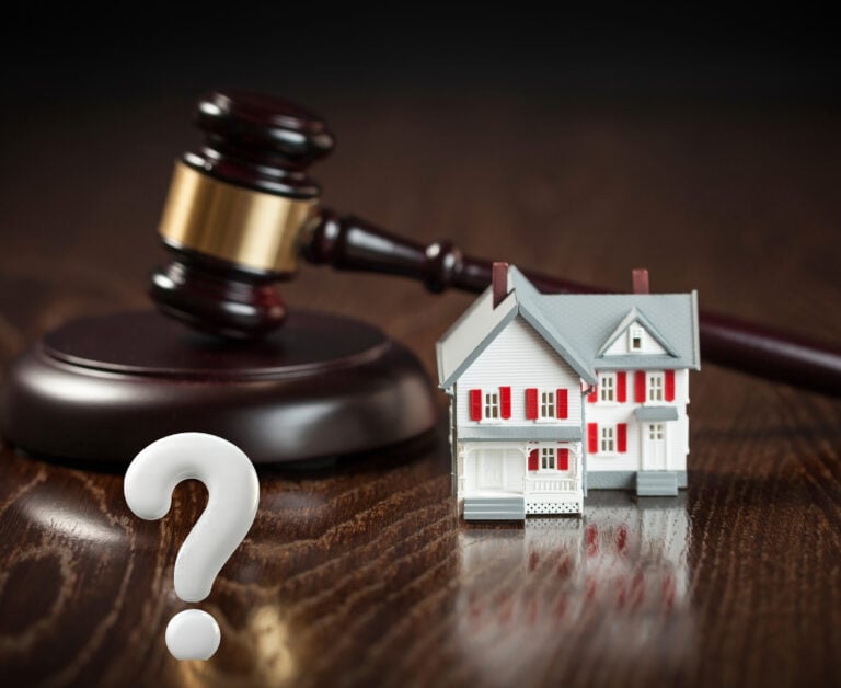 A justice hammer, white question mark and a model house sitting on a desk