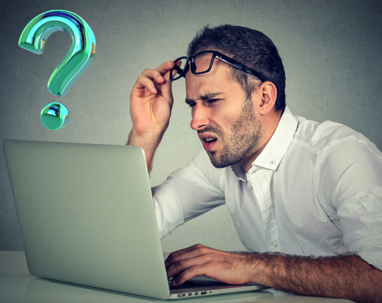 A man sitting at a laptop, looking confused and a green question mark