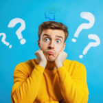 A man wearing a yellow top on a blue background with Question marks