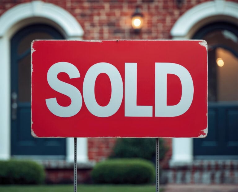 Sold sign with houses in the background
