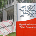 Welsh logo with Welsh Government alongside a compensation sign and a building in the background