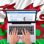 A person tying on a laptop sitting on a Welsh flag
