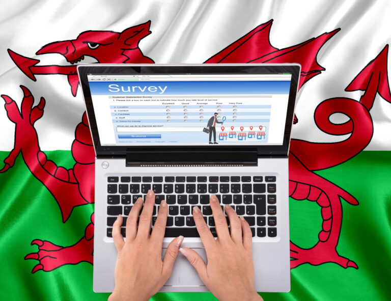 A person tying on a laptop sitting on a Welsh flag