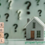 Sell written onto small building blocks next to a model house and questions marks in the background