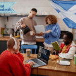 Students around a dining table, a student sitting at the table on a latop wearing headphones and a Scottish flag