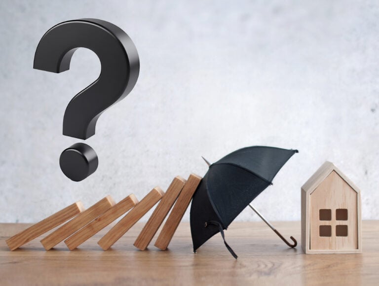 Black question mark, wooden dominoes against an umbrella and a small wooden house