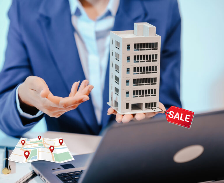 Buisnessman with a laptop holding office block for sale with a location map on the desk