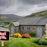 Cottage with backdrop of mountains and lake, and a Council tax bill sign
