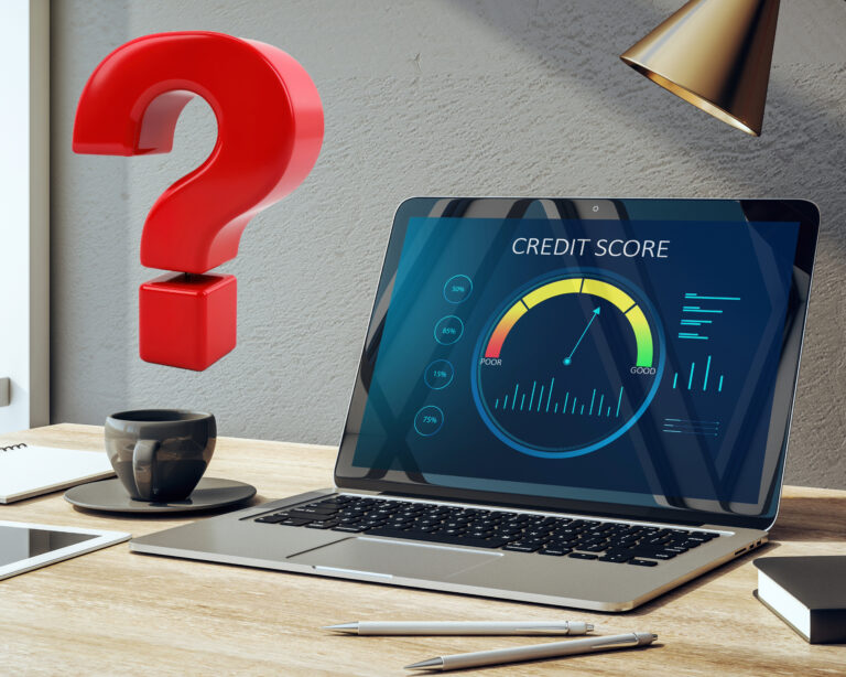 Laptop showing a credit score report on a desk with pens and a book, a red question mark sign above a coffee cup
