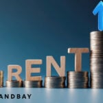 Coins stacked with a blue arrow pointing upwards and the words RENT balanced on top of the coins