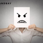 man holding up an angry face over his head