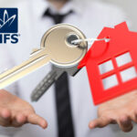 A man in a shirt and tie with Keys on a keyring of a red house in his open hands