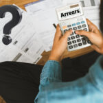 Man on calculater with paperwork and a question mark