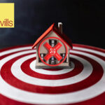 Small house with red X sign on top of white and red circles with Savills logo