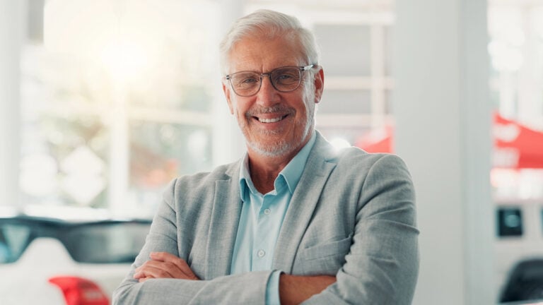 A man in a suit looking happy with his arms crossed