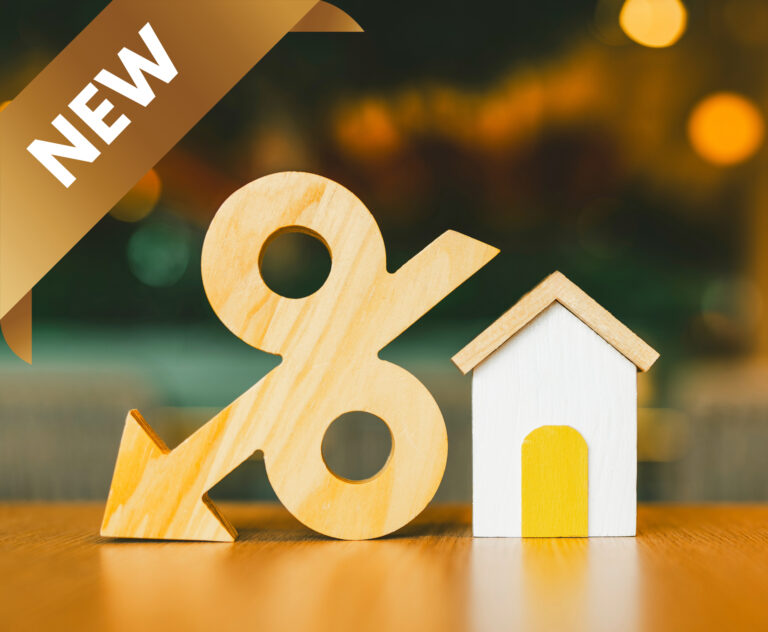 Wooden percentage symbol with downward arrow beside small house model, symbolizing reduced mortgage rates.