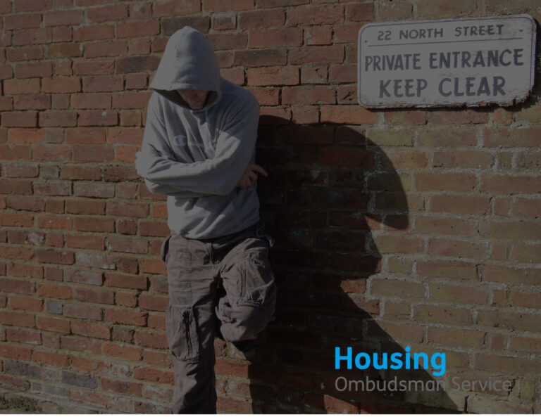 Muted photo with a youth in a hoodie leaning up against a wall