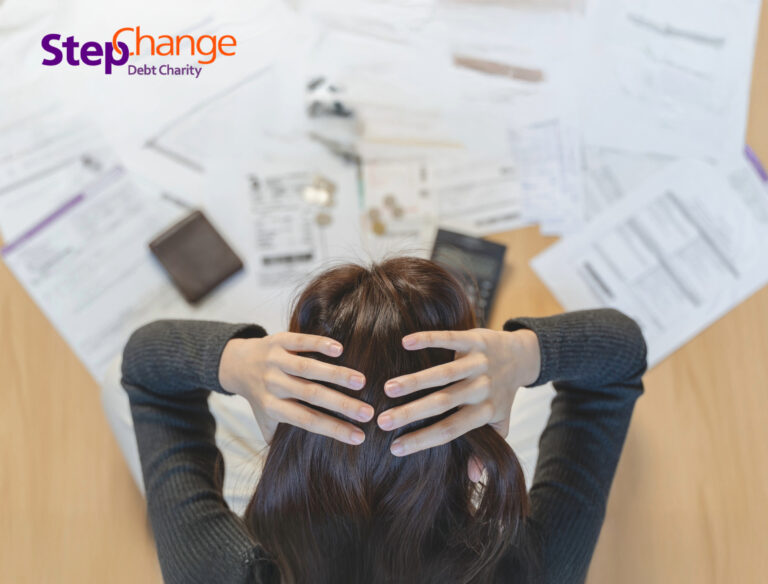 Person stressed over bills and debt paperwork, highlighting financial struggles of private renters