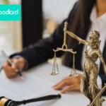 sopmneone sitting at desk signing with the lady of justice