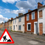 Row of empty derelict houses with a building hazard warning sign